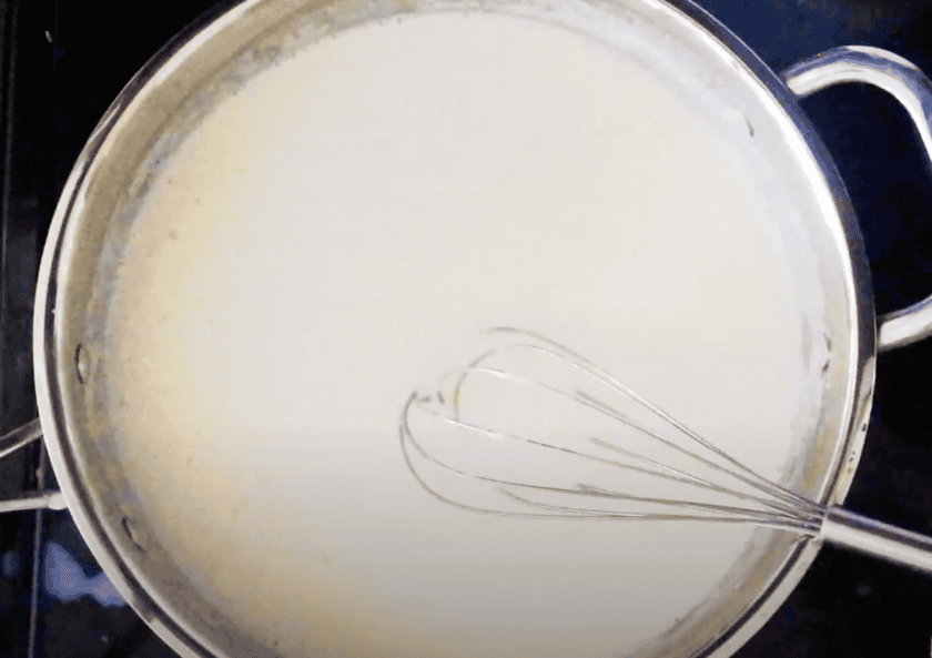 A creamy sauce being made in a skillet with a whisk