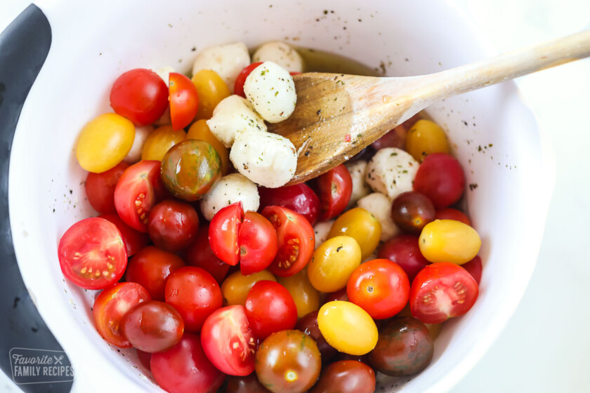 A mixing bowl with cherry tomatoes and mozzarella.