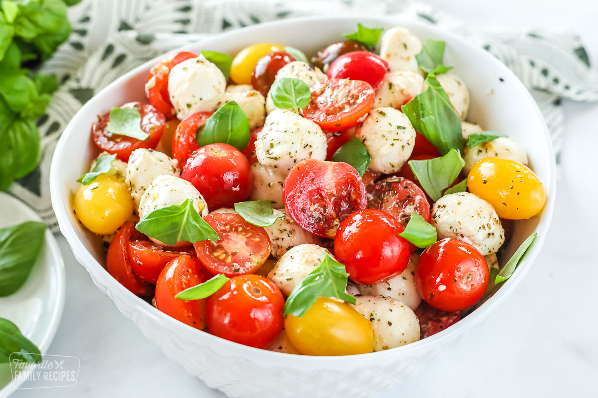 A side-view of a large bowl of caprese salad made with tomatoes, mozzarella, and basil.