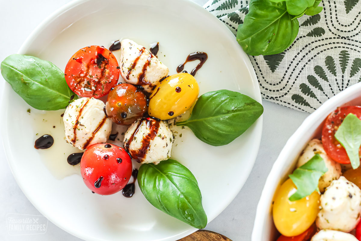 A plate with cherry tomatoes, mozzarella, basil, olive oil, and a drizzle of balsamic vinegar reduction.