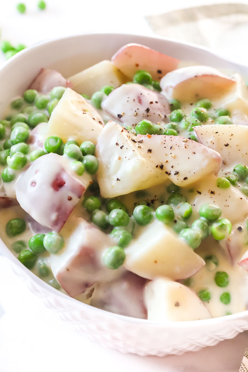 A close up view of creamy potatoes and peas in a bowl.