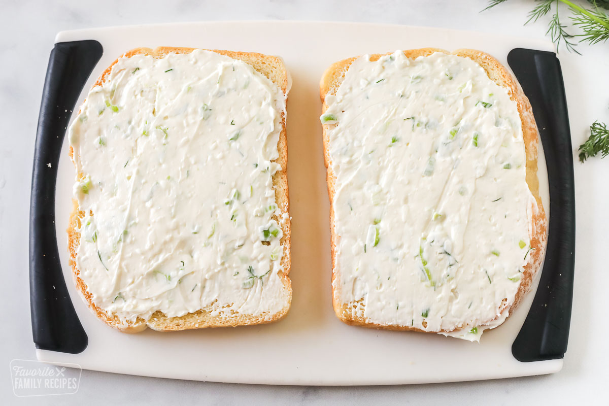 Two slices of bread with a cream cheese spread to make cucumber sandwiches