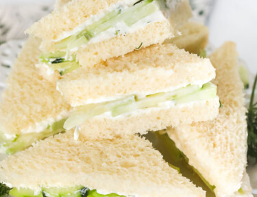Cucumber sandwich wedges on a white serving platter