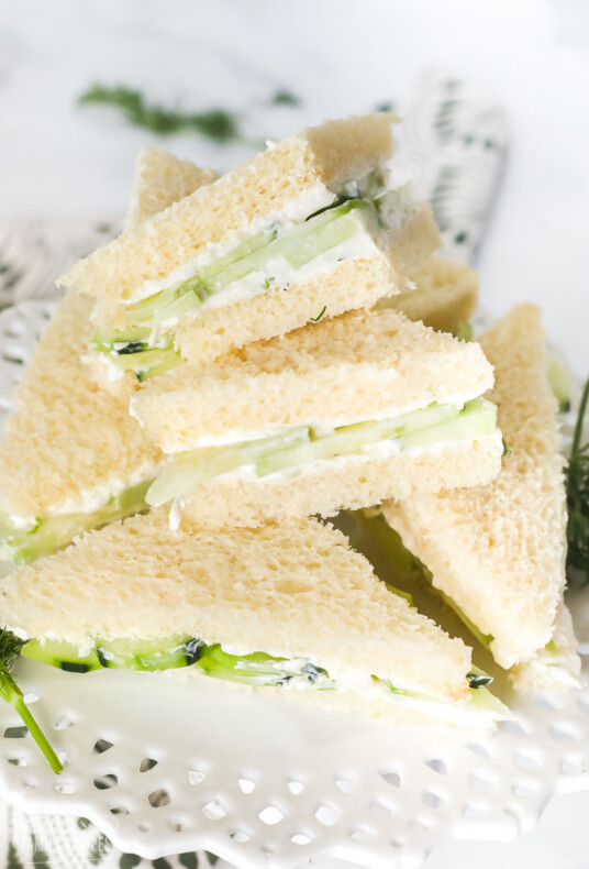 Cucumber sandwich wedges on a white serving platter