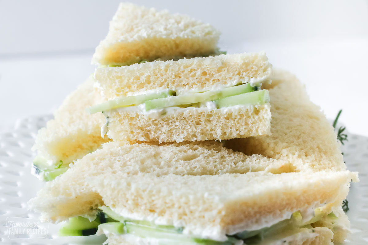 Cucumber tea sandwiches stacked on a white serving platter