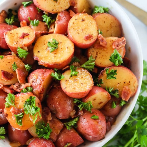 German potato salad made with red potatoes, vinegar, onion, bacon, and parsley in a bowl.