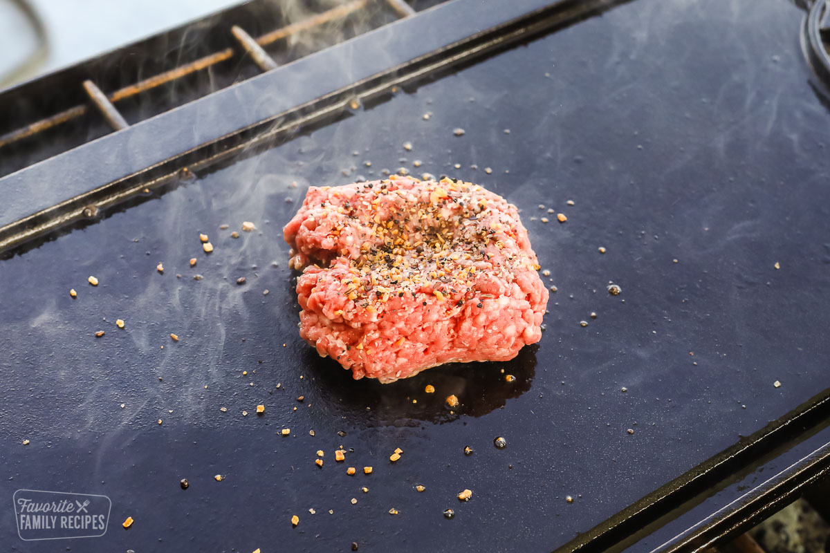 Ground beef on a cast iron griddle with seasonings