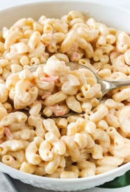 A spoon taking a scoop of Hawaiian macaroni salad from a serving bowl