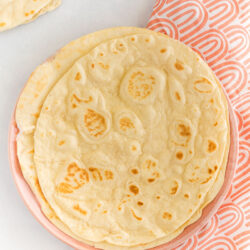A stack of homemade flour tortillas on a plate