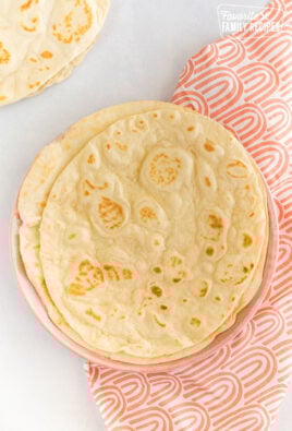 A stack of homemade flour tortillas on a plate