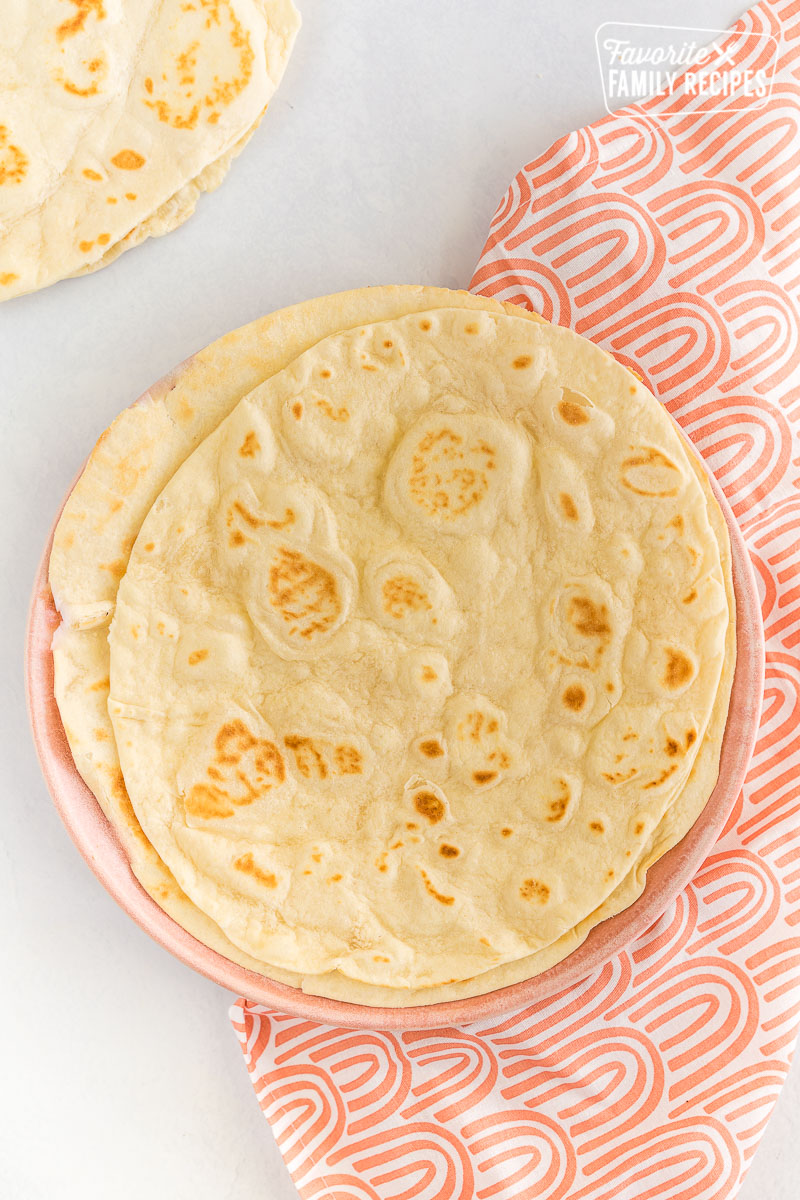A stack of homemade flour tortillas on a plate