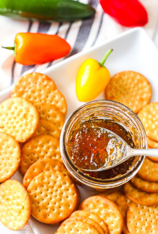 A jar of hot pepper jelly made with jalapeños and a plate of crackers