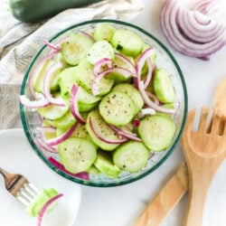 Cucumber salad with marinated cucumbers in a bowl and a plate with a fork holding a bite-sized piece