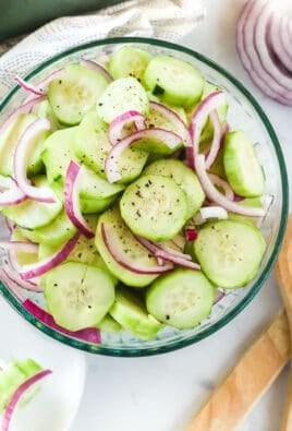 Cucumber salad with marinated cucumbers in a bowl and a plate with a fork holding a bite-sized piece