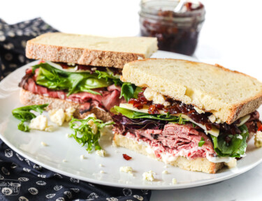 A roast beef sandwich with deli roast, lettuce, cheese, and bacon jam.