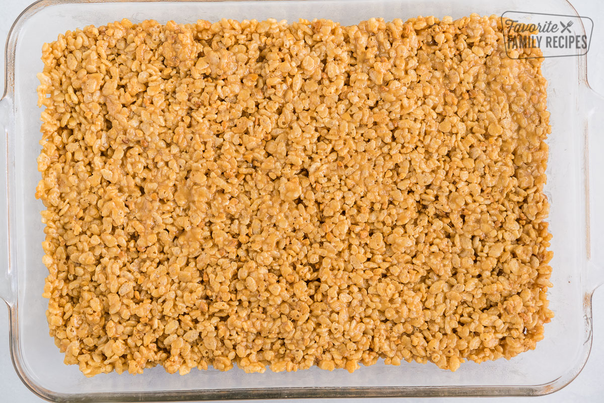 Rice krispie base of Scotcharoos pressed into a 9x13 glass baking pan
