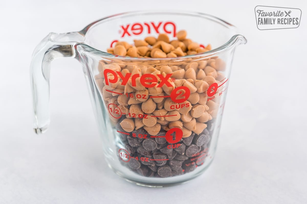 These no-bake Scotcharoos, also known as Oh Henry Bars, are a favorite treat. A Rice Krispie and peanut butter center is covered with a chocolate butterscotch topping. Chocolate chips and butterscotch chips in a clear measuring cup.