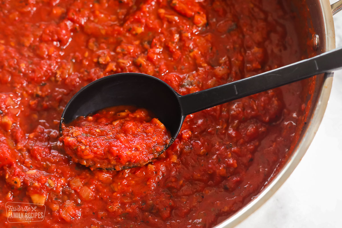 A close up of homemade spaghetti sauce in a skillet with a serving spoon