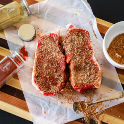Two cuts of steak rubbed with a dry rub on a cutting board