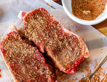 Two cuts of steak with dry rub on them.