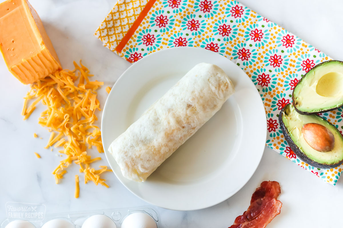 A rolled breakfast burrito on a plate
