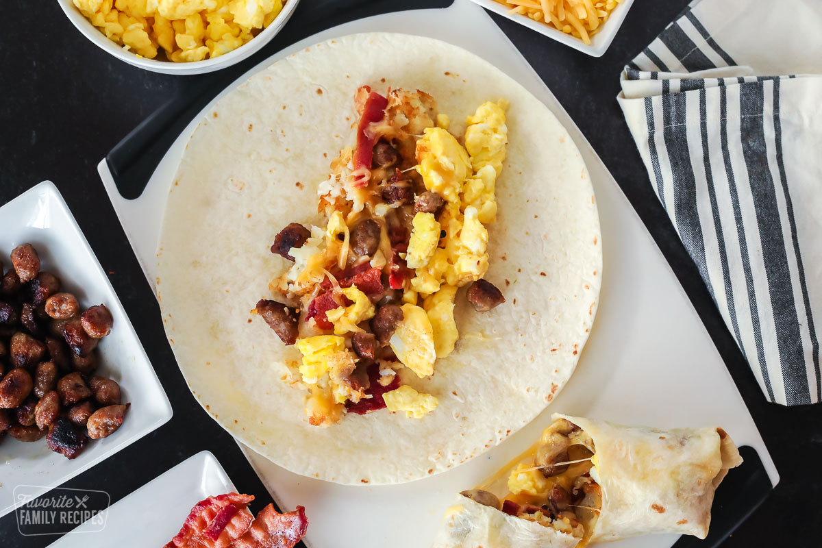 Eggs, sausage, cheese, bacon, and hash browns on a flour tortilla