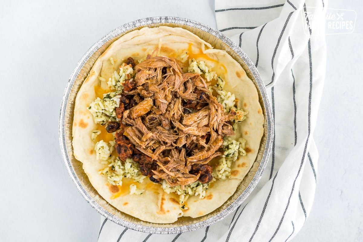 A tortilla filled with cheese, rice, beans, and pork