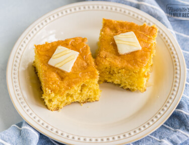 Two pieces of cornbread on a plate with butter and honey