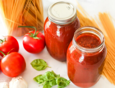 One opened jar of spaghetti sauce next to an unopened jar