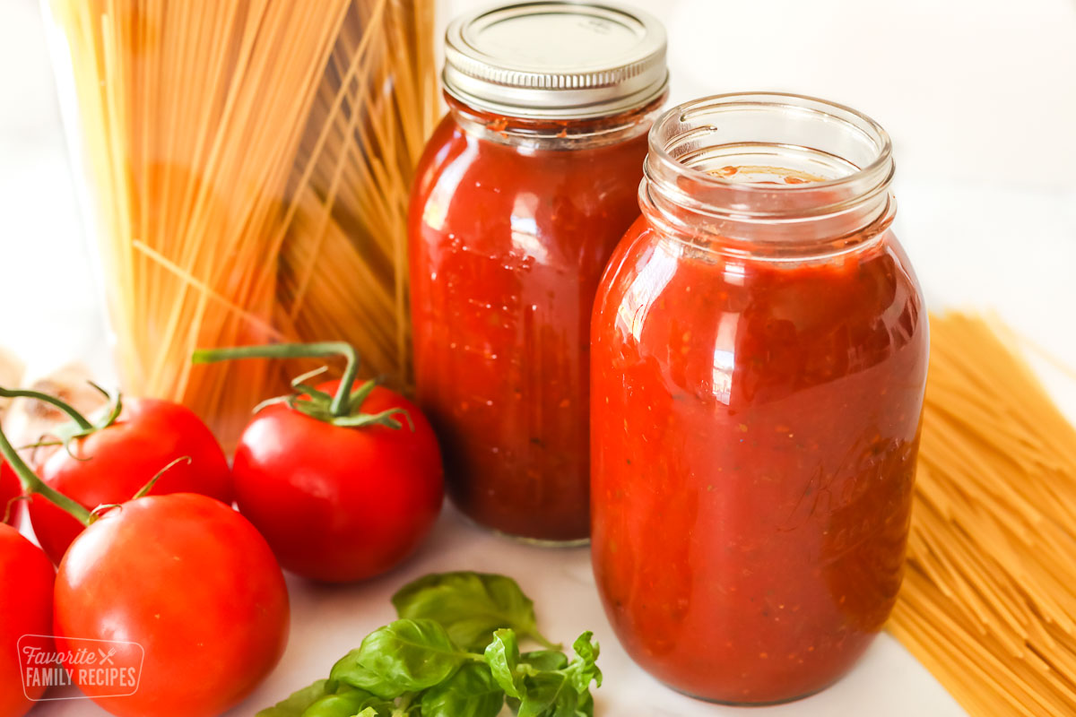 Two jars of homemade canned spaghetti sauce next sauce ingredients.