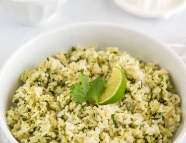 A bowl of cilantro lime rice next to a juicer and a bowl of lime