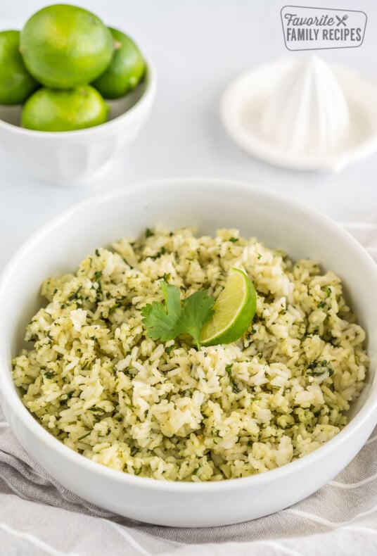 A bowl of cilantro lime rice next to a juicer and a bowl of lime