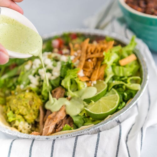 Dressing being poured over a salad