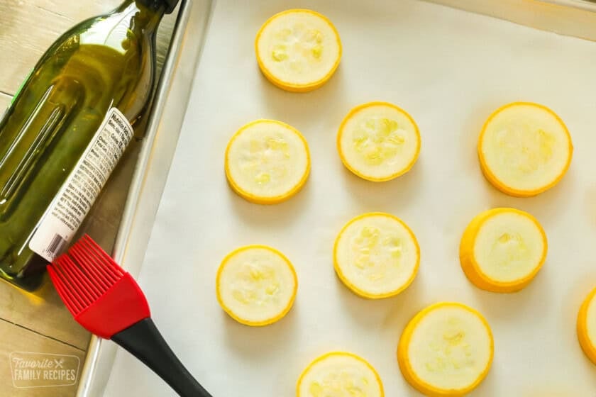 Sliced Summer squash on a baking sheet with olive oil ready to be roasted