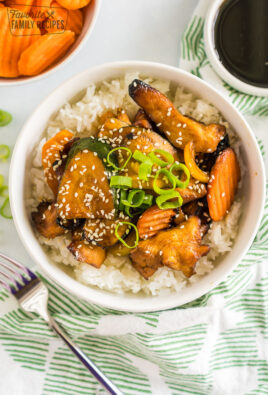 A bowl of white rice topped with chicken and vegetables