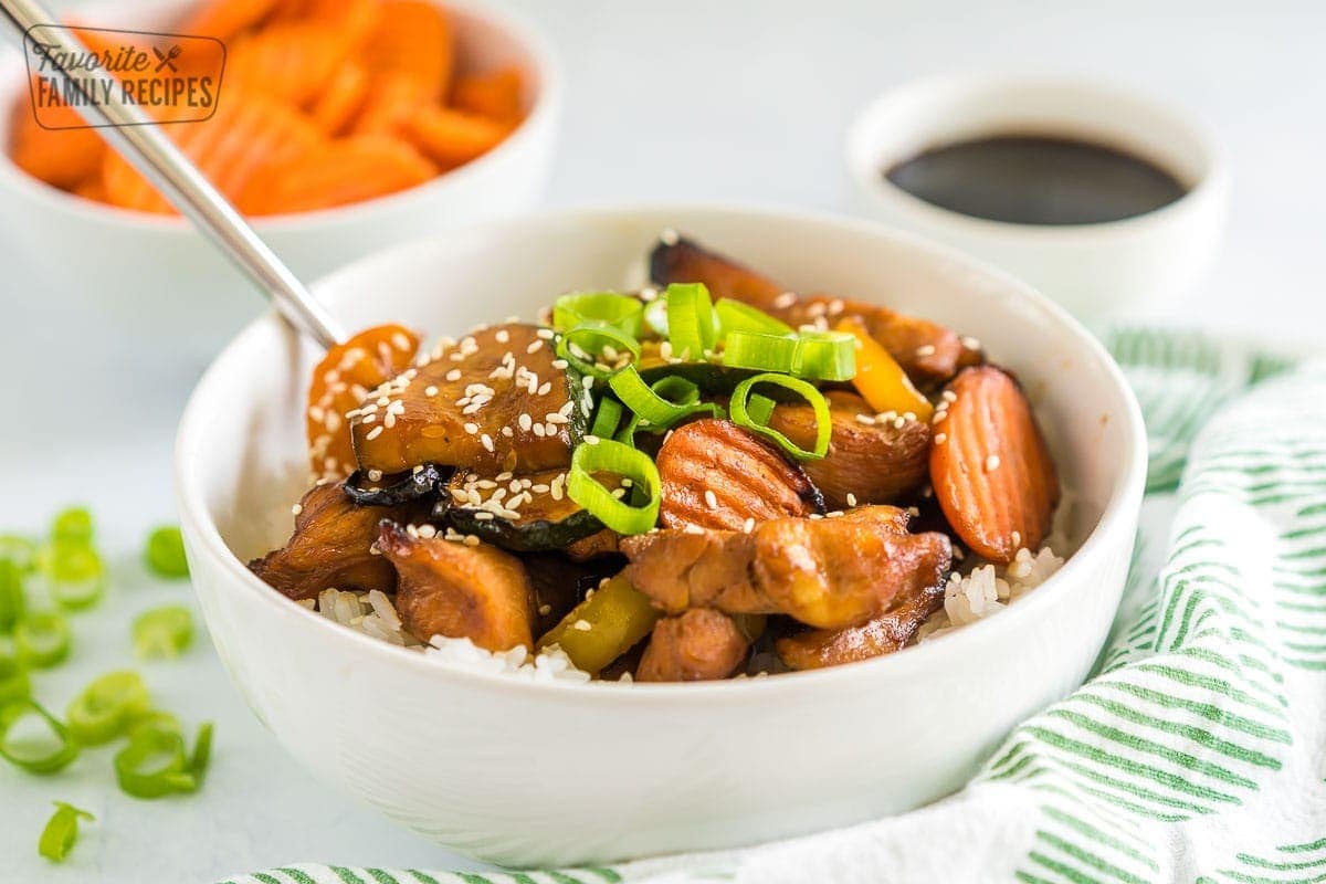 A bowl of white rice topped with chicken teriyaki and vegetables