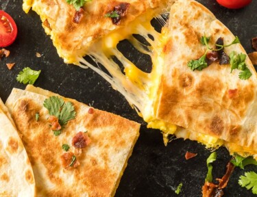 Quesadillas that have been grilled on a skillet until golden brown. They are filled with cheese, scrambled eggs, and bacon.