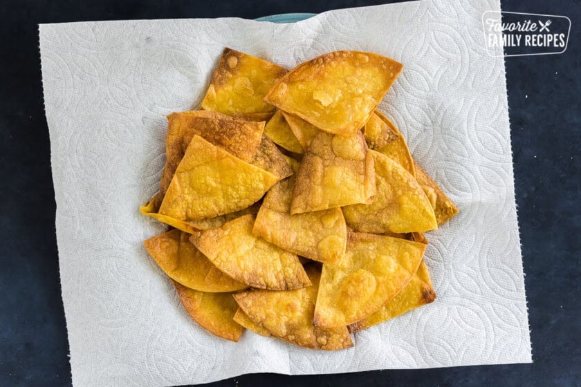 Lightly fried corn tortillas on a plate with a paper towel.