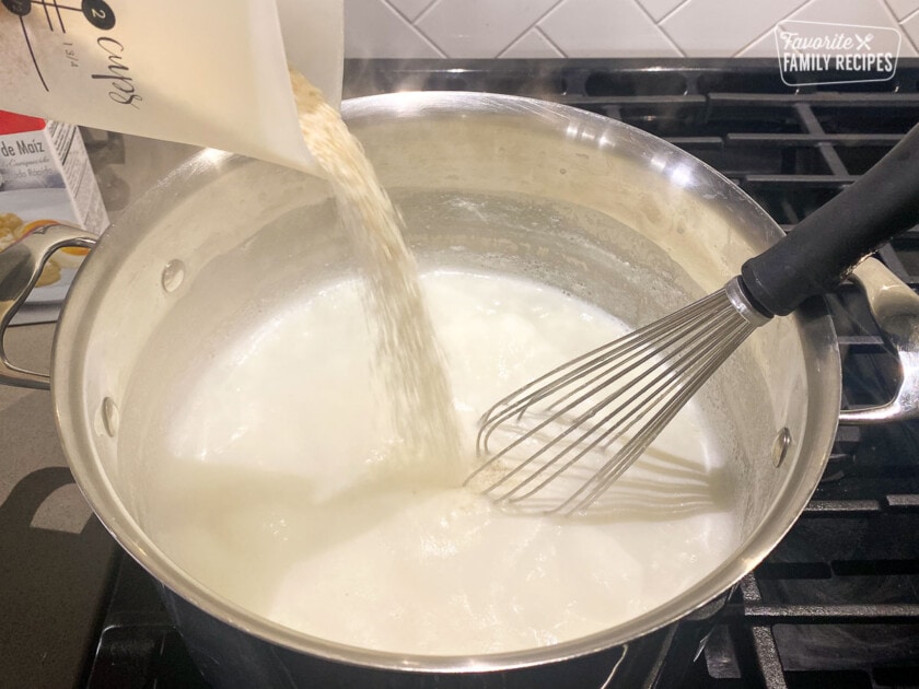 Pouring grits into liquid in a pan