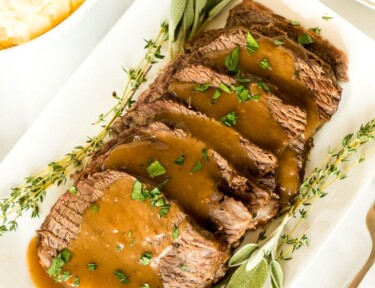 Oven roast beef on a platter with gravy and garnish