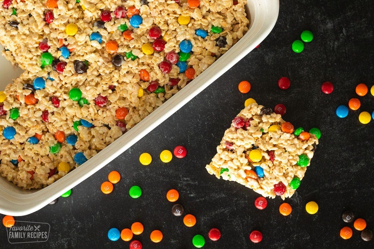 A Rice Krispie treat next to a pan of Rice Krispie treats.