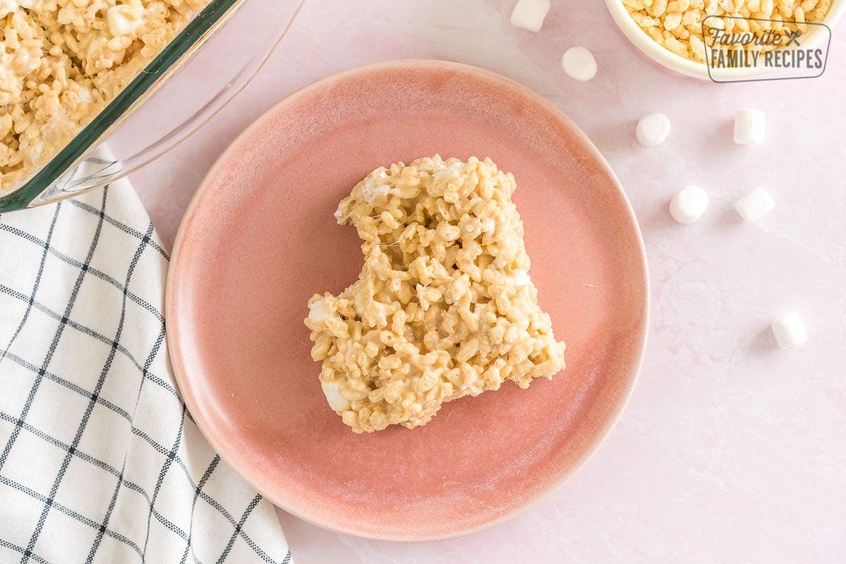 A salted caramel rice krispie treat with a bite taken out of it on a plate.