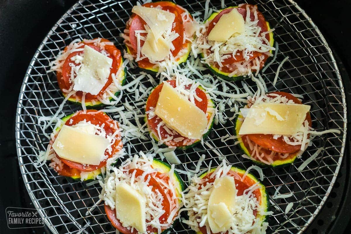 Uncooked zucchini pizza bites on an air fryer rack