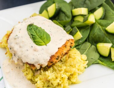 Parmesan Crusted Chicken in Basil Cream Sauce on a plate with a spinach salad