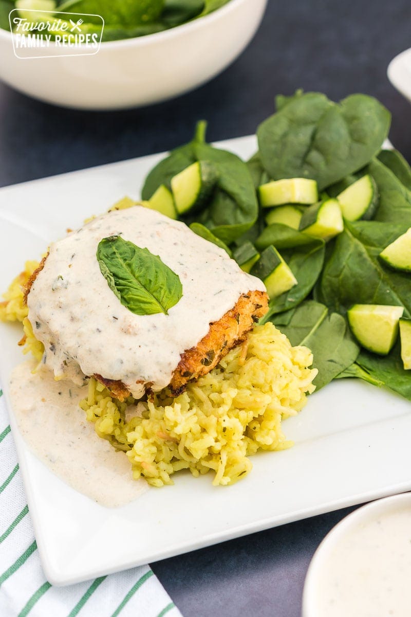 Parmesan Crusted Chicken in Basil Cream Sauce on a plate with a spinach salad