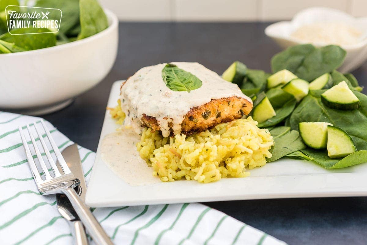 Parmesan Crusted Chicken in Basil Cream Sauce on a plate with a spinach salad