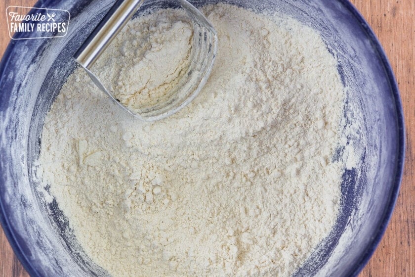 Flour and shortening mixed together in a bowl with a pastry cutter.