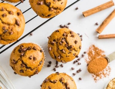 Pumpkin chocolate chip muffins on a cooling rack with some on the counter