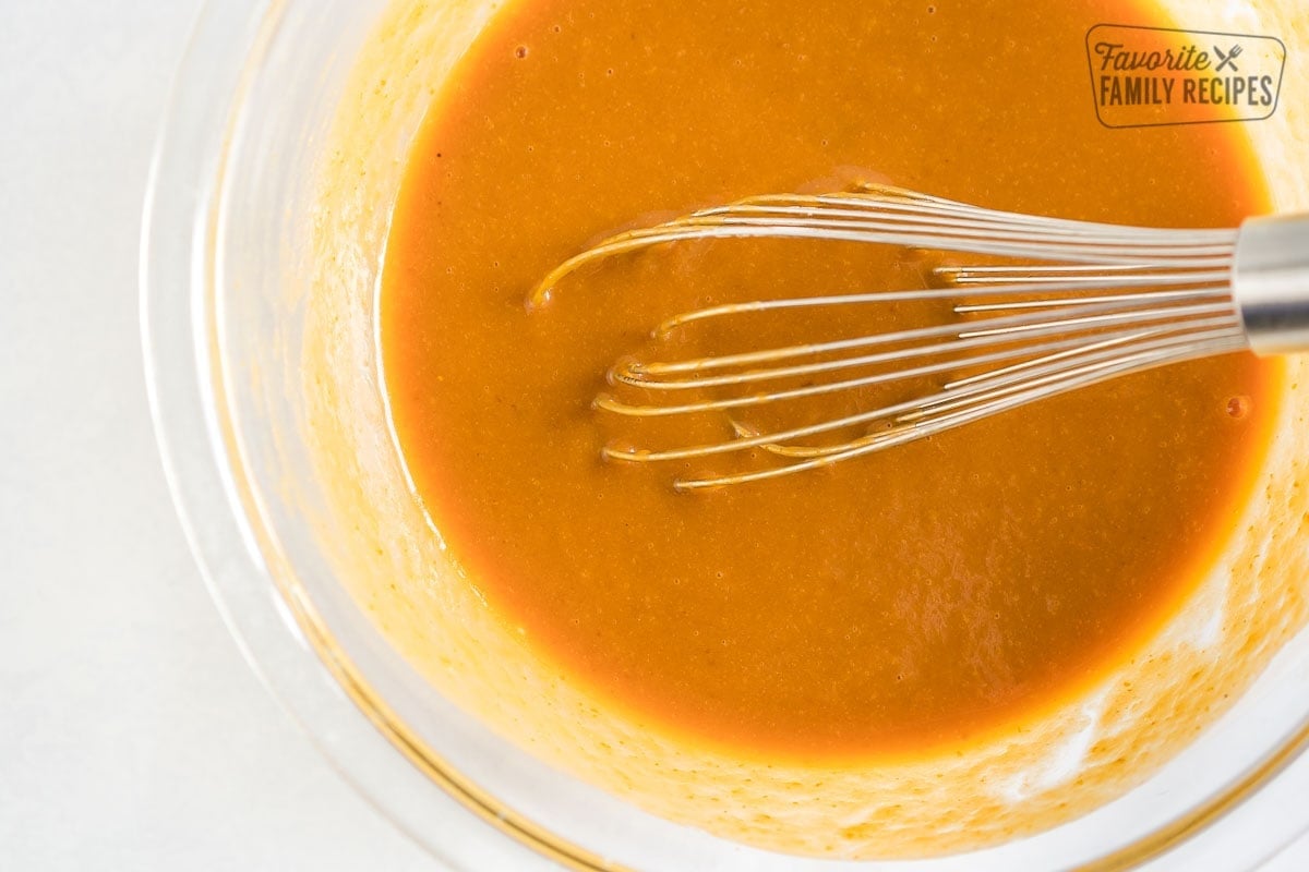 A glass bowl full of pumpkin, buttermilk, eggs, and brown sugar