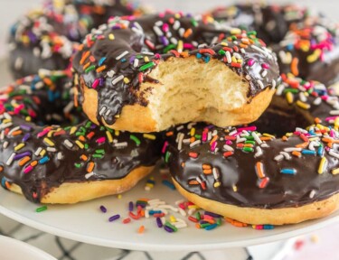 A platter of chocolate sprinkle air fryer donuts with a bite taken out of one